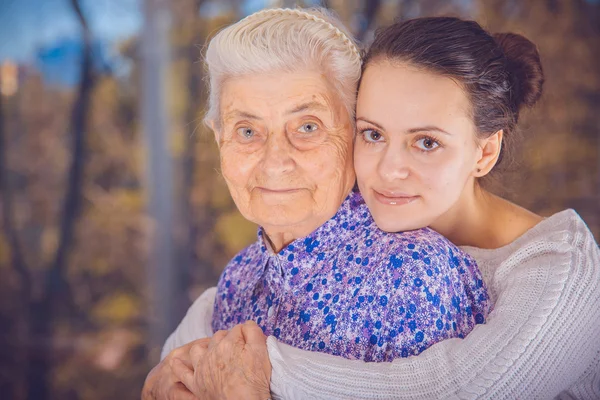 Молодая девушка и пожилая бабушка. Девушка обнимает бабушку — стоковое фото