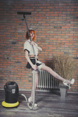 Hizmetçi. Bir kadın bir hizmetçi kostümü giymiş. H temizlik yapar