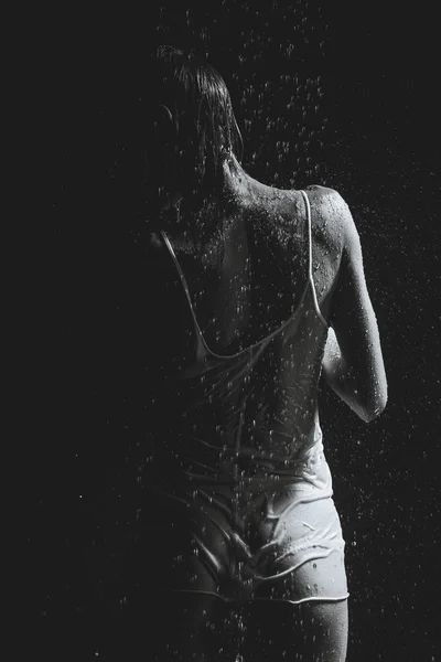 Ducha. Chica en una camiseta blanca de pie bajo una ducha. Negro a —  Fotos de Stock