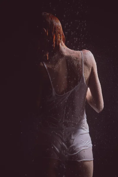 Chuveiro. Menina em uma camiseta branca em pé sob um chuveiro . — Fotografia de Stock