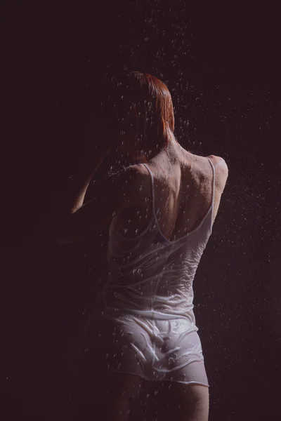Chuveiro. Menina em uma camiseta branca em pé sob um chuveiro . — Fotografia de Stock
