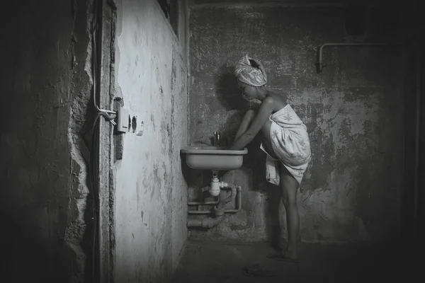 Cheap accommodation. The girl washing her feet in the sink. Blac — Stock Photo, Image