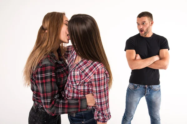 Das Mädchen küsst ein Mädchen. Mann unter Schock. — Stockfoto