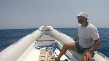 Bir tekne. Bir adam açık denizlerde bir motorlu teknede yelken açıyor. Mısır. Kızıl Deniz.