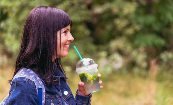 Drink. The girl drinks a drink from a plastic glass with a plastic tube.