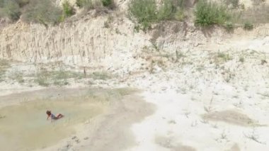 Güneş banyosu. Mayo giymiş bir kadın çölün ortasında küçük bir su birikintisinde yüzer. Hava görünümü