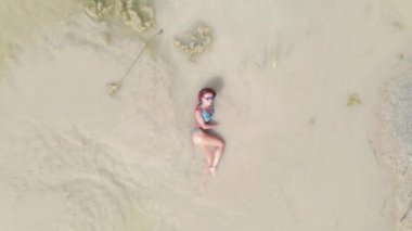 Güneş banyosu. Mayo giymiş bir kadın çölün ortasında küçük bir su birikintisinde yüzer. Hava görünümü