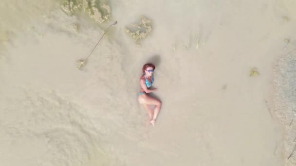 日光浴一个穿着泳衣的女人在沙漠中央的一个小水坑里游泳 空中景观 — 图库视频影像