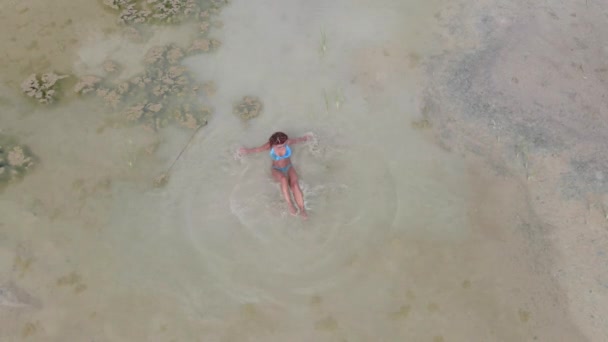 日光浴 砂漠の真ん中の小さな水たまりの中で水着姿の女性が泳いでいます 空中風景 — ストック動画