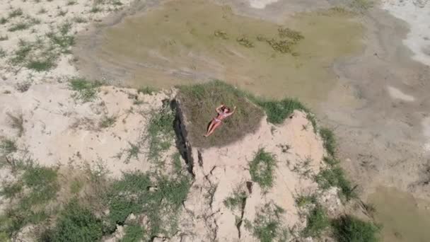 日光浴 階段の途中にある砂の山の上で水着姿の女性が日光浴をしている 空中風景 — ストック動画