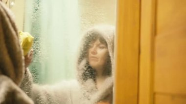 Tuvalette. Banyoda bir kadın aynayı yıkıyor..