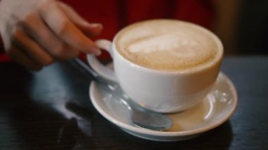 Kapuçino. Bir kadının eli bir fincan kapuçino alır..