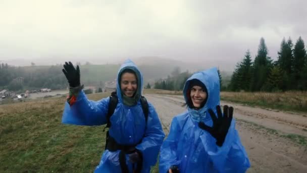 Płaszcz Przeciwdeszczowy Dwie Kobiety Płaszczach Przeciwdeszczowych Machające Rękami — Wideo stockowe