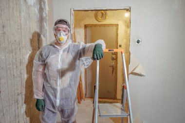 Daire tadilatı. Koruyucu giysili, solunum cihazı ve gözlüklü müteahhit..