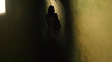 Tünel. Bir kadın uzun ve dar bir tünelde yürüyor..