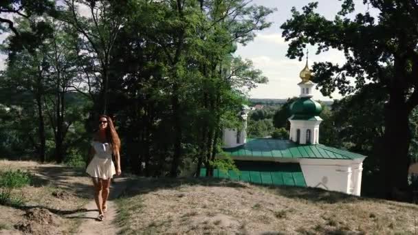 Caminhadas Uma Mulher Caminha Parque Contra Pano Fundo Igreja — Vídeo de Stock