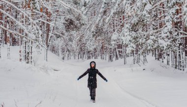 Kış. Karlı bir ormanın arka planında ceketli ve şapkalı bir kadın..
