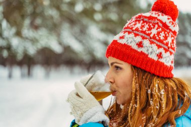 - Çay. Kış parkında bir kadın termostan çay içer..