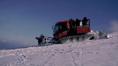 Pylypets, UKRAINE - 24 Şubat 2021. Raylardaki traktör kayakçıları ve snowboardcuları dağın zirvesine taşıyor..