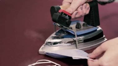 Demir gibi. Ütü işlemeli yüz maskesini ütülüyor. Yakın plan..