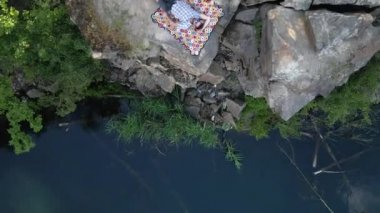 Kariyer. Bir adam gölün yanındaki granit bir kayanın üzerinde yatıyor. Hava görünümü.