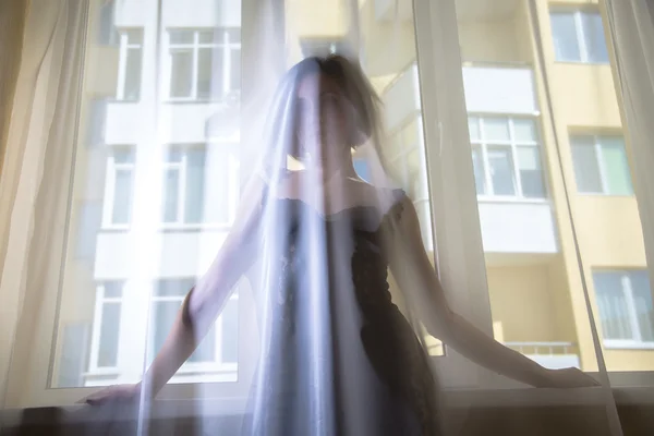 Una chica mira por la ventana — Foto de Stock