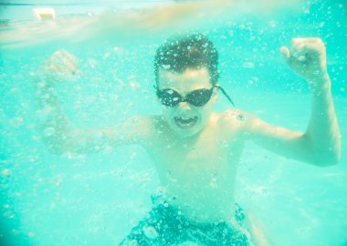 Bir çocuk kasları su altında bir yandan gösterir.