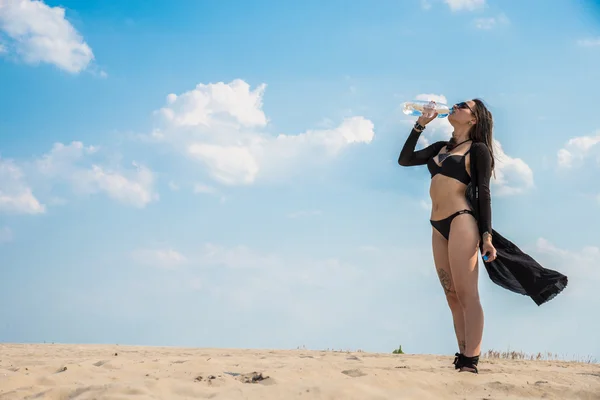 Meisje in woestijn drinkwater uit een plastic fles — Stockfoto