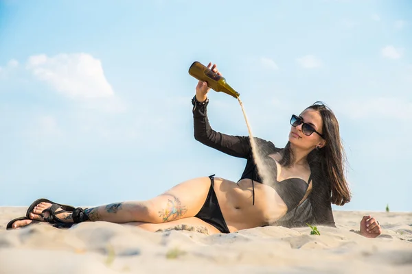 La chica está en el desierto y la arena se derrama de la botella —  Fotos de Stock