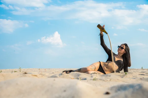 Het meisje is in de woestijn en zand giet uit de fles — Stockfoto