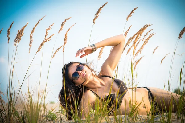 Het meisje ligt op een achtergrond van tarwe oren — Stockfoto