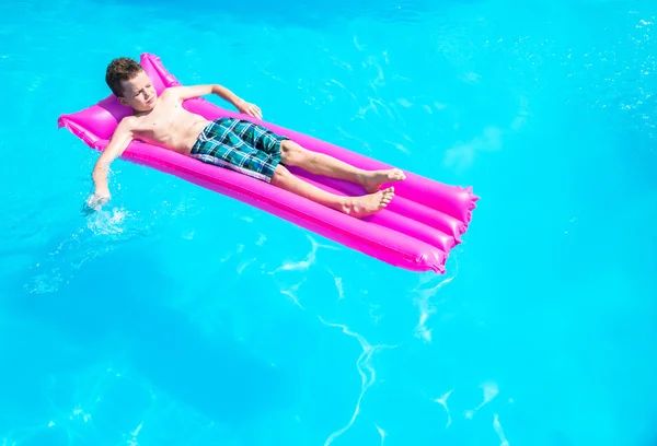 Ένα αγόρι που επιπλέει σε ένα φουσκωτό στρώμα στην πισίνα — Φωτογραφία Αρχείου