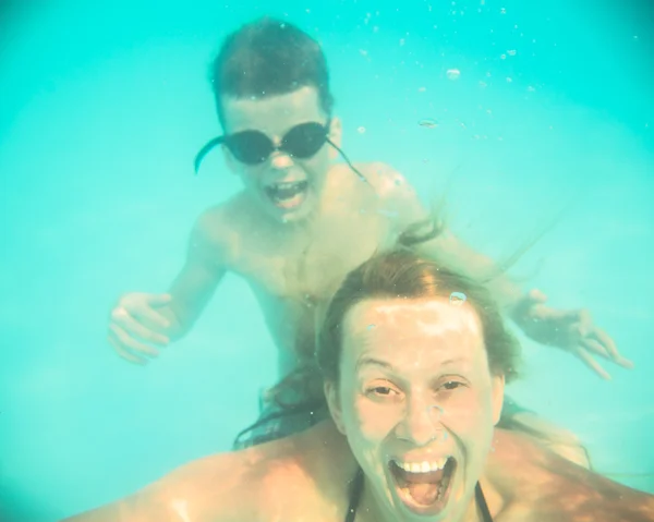 Mor och son grimas under vatten i poolen — Stockfoto