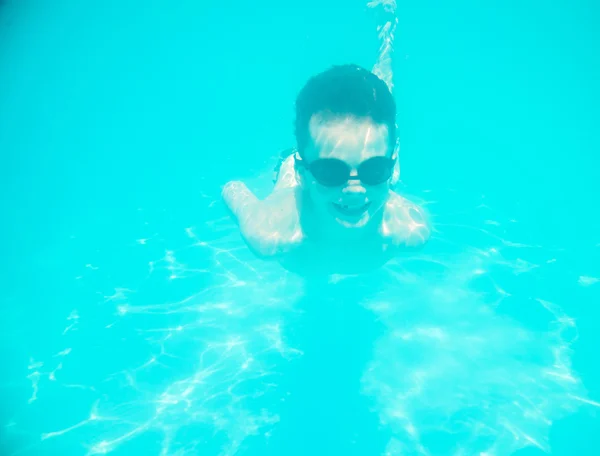 En liten pojke som simmar under vattnet i poolen — Stockfoto