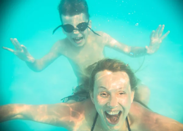 Madre e hijo hacen muecas bajo el agua en la piscina — Foto de Stock