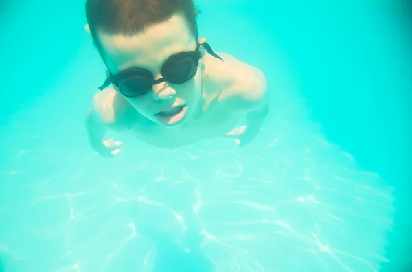 En liten pojke som simmar under vattnet i poolen — Stockfoto