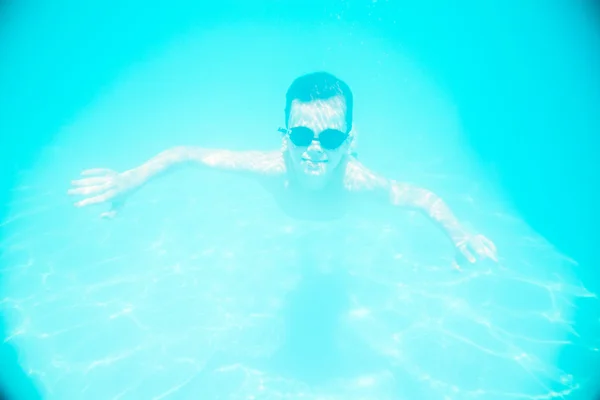 Um menino nadando debaixo d 'água na piscina — Fotografia de Stock