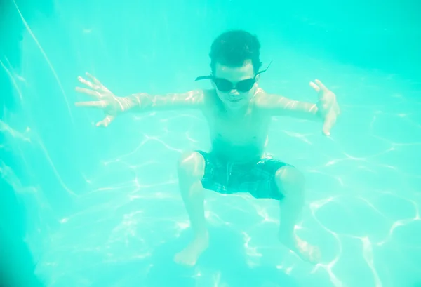 Um menino nadando debaixo d 'água na piscina — Fotografia de Stock