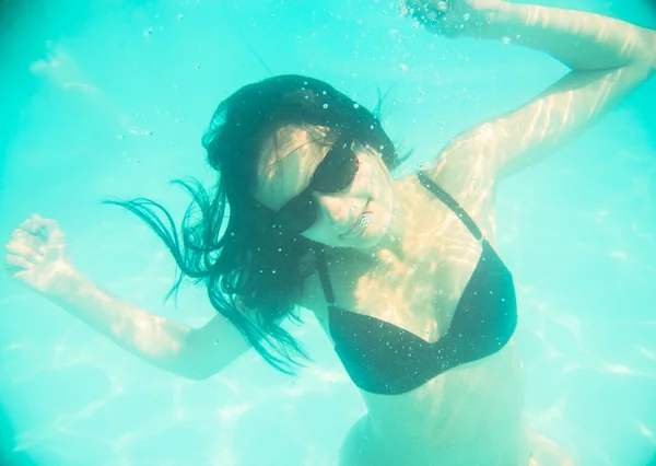 Girl swimming underwater in sunglasses — Stock Photo, Image