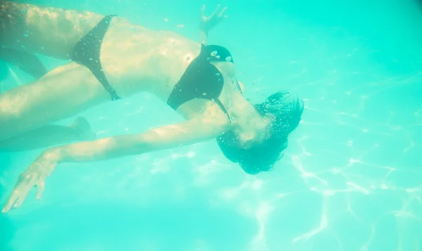 Flicka simma under vattnet med ögonen öppna — Stockfoto