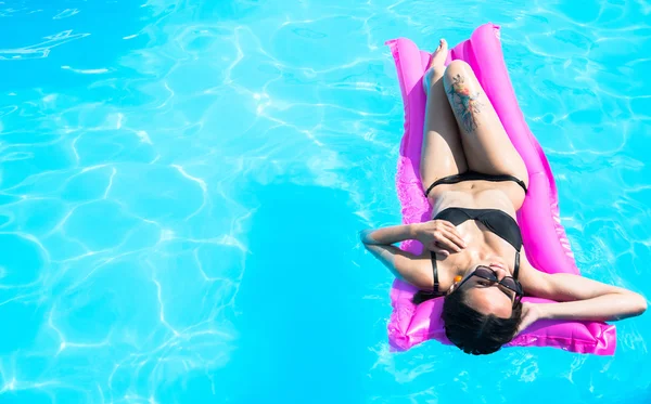 A lány a medencében úszik egy felfújható matracon. — Stock Fotó