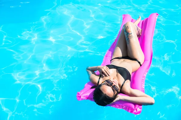 Meisje zwemt in het zwembad op een opblaasbare matras — Stockfoto