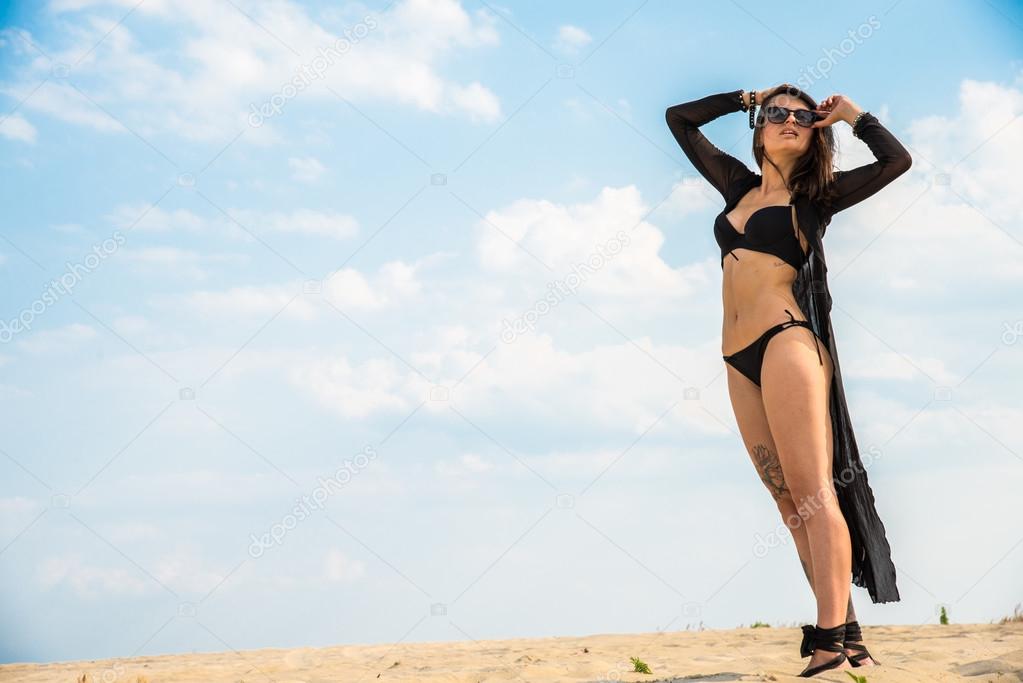 Girl in black swimsuit jumping on the background of the desert