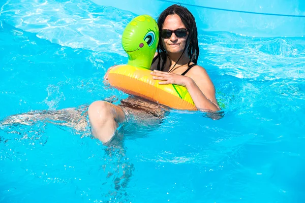 Ragazza nuota in piscina su un cerchio gonfiabile — Foto Stock