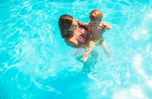 Madre joven bañándose en la piscina con su hijo — Foto de Stock