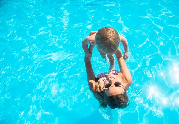 Jovem mãe tomando banho na piscina com seu filho — Fotografia de Stock