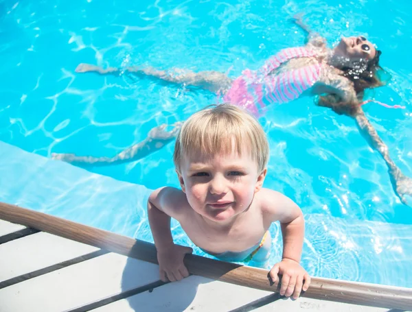 Madre joven bañándose en la piscina con su hijo — Foto de Stock