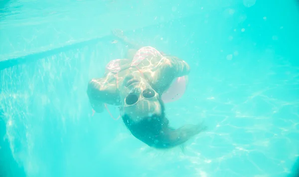 Young girl in sunglasses swimming underwater — Stock Photo, Image