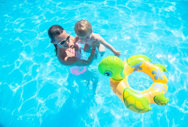 Madre joven bañándose en la piscina con su hijo — Foto de Stock