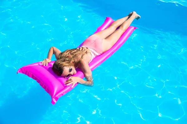 The girl floats on an inflatable mattress in the pool — Stock Photo, Image